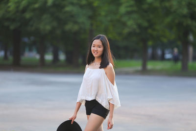 Portrait of young woman standing on road