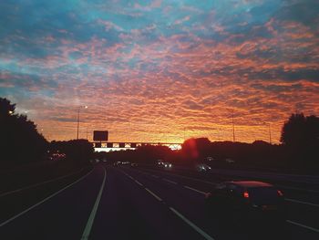 Cars on road against sky during sunset