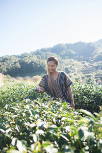 Smiling young woman standing amidst tea crops 