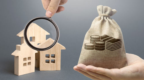 Money bag, wooden houses on a gray background. buy purchase and sale of housing