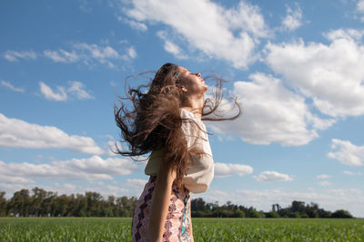 Rear view of woman standing on field against sky