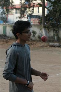 Teenage boy tossing ball while playing cricket