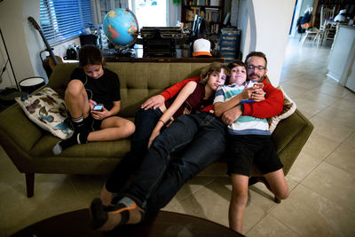 Father and his three children snuggle on couch