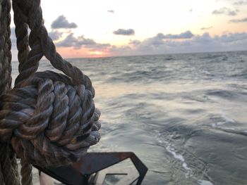 Close-up of rope on beach against sky during sunset