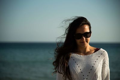 Portrait of woman wearing sunglasses at beach against sky