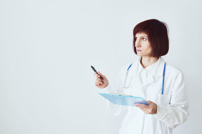 Young woman using smart phone against white background