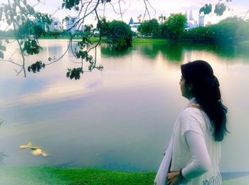 Young woman by lake against sky