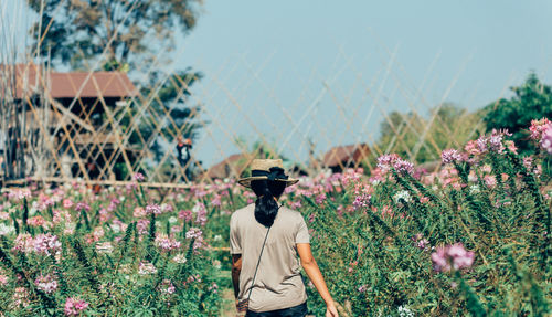 Rear view of person standing by flowering plants