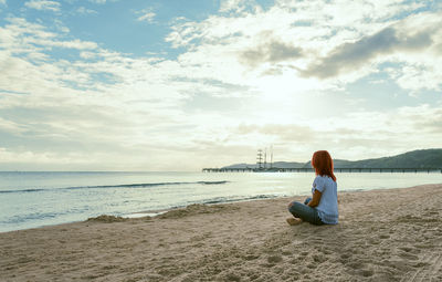 Rear view of woman sitting on beach