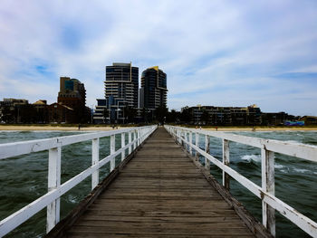 Pier amidst buildings in city against sky