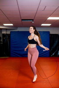 Portrait of a smiling young woman standing on tiled floor