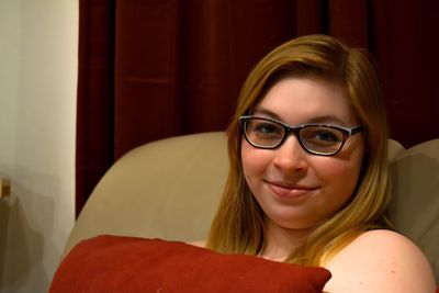 Close-up portrait of young woman sitting on sofa