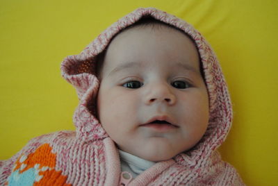 Cute baby girl wearing knitted warm clothing lying on bed