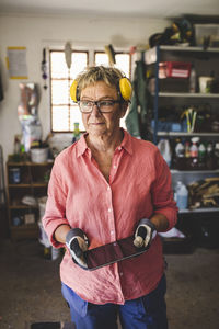 Thoughtful senior woman holding digital tablet while standing at workshop