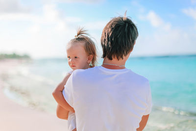 Rear view of siblings at beach against sky