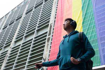 Low angle view of young man standing against buildings