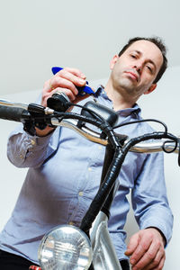 Portrait of young man holding bicycle against white background