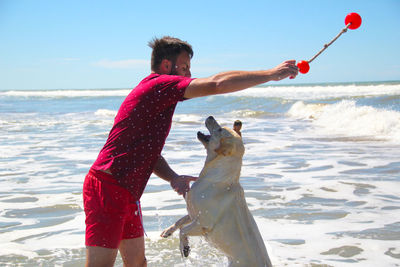 Side view of shirtless man at beach against sky