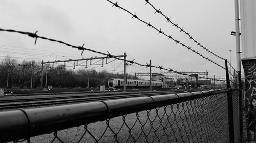 Close-up of barbed wire fence against sky