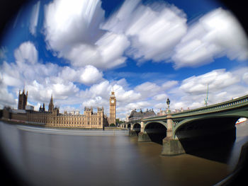 Arch bridge over river against sky in city