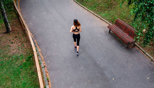 Top view of female athlete backwards running on a road