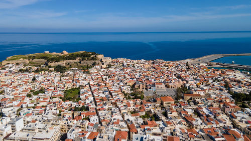 High angle view of townscape by sea against sky