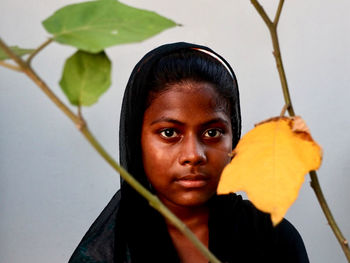 Close-up portrait of young woman with leaves