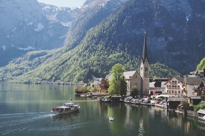 Boats in lake by buildings against mountains