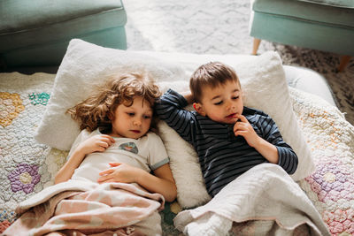 Brother and sister laying in livingroom together watching movie