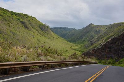 Road leading towards mountains against sky