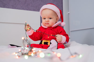 Cute baby playing with christmas lights at home