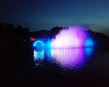 Scenic view of illuminated lake against sky at night