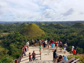 People on mountain against cloudy sky