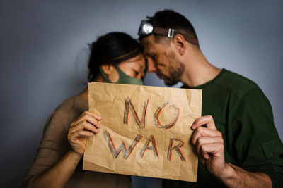 Upset couple homeless protesting war conflict raises banner with inscription message text no war. 