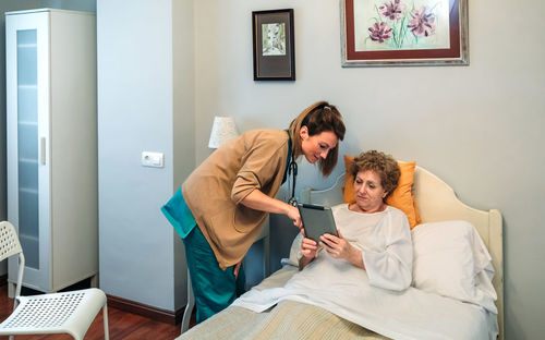 Nurse showing digital tablet to senior patient in hospital