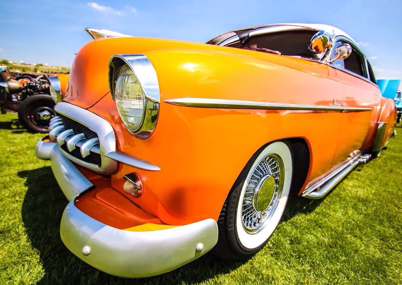 transportation, mode of transport, land vehicle, car, wheel, yellow, stationary, field, vintage car, close-up, travel, headlight, grass, part of, outdoors, sunlight, sky, no people, parking, day