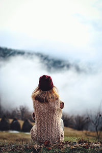 Rear view of woman walking on field against sky