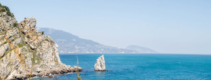 Scenic view of sea and mountains against clear sky