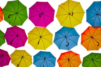 Multi colored umbrellas hanging against white background