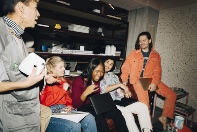 Smiling male and female entrepreneurs discussing while working in creative office