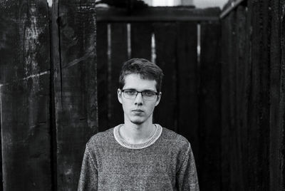 Portrait of young man standing against abandoned wooden structure