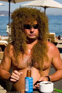 Shirtless man wearing wig at beach on sunny day