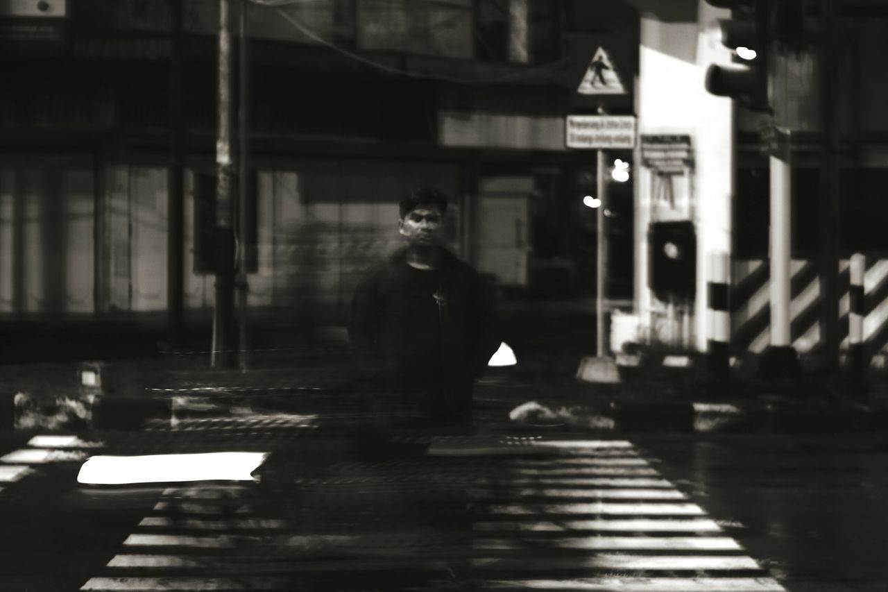 MAN WALKING ON ILLUMINATED STREET