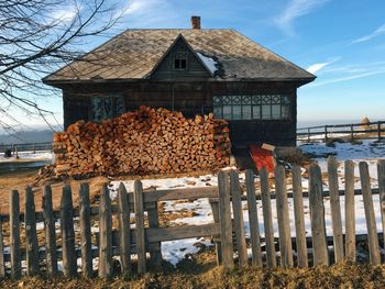 Logs by house during winter on sunny day