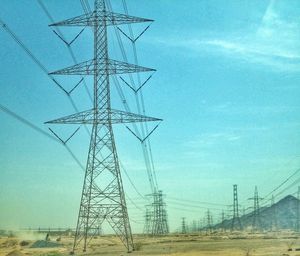 Electricity pylon on field against blue sky