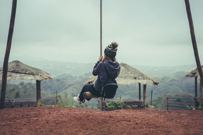 Rear view of person on swing at playground