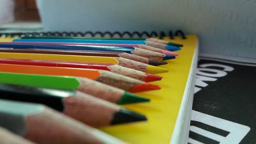 Close-up of colored pencils on spiral notebook