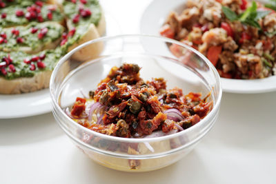 Close-up of food in bowls and plate on white table