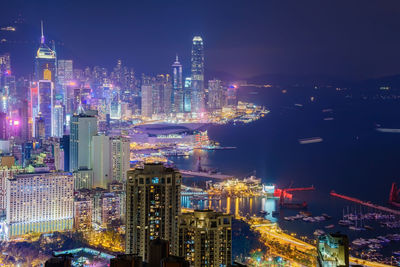 Illuminated modern buildings in city against sky at night