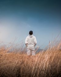 Rear view of man standing on field against sky